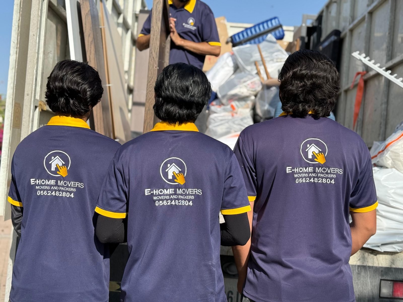 Uniformed villa movers in Dubai loading furniture onto a moving truck